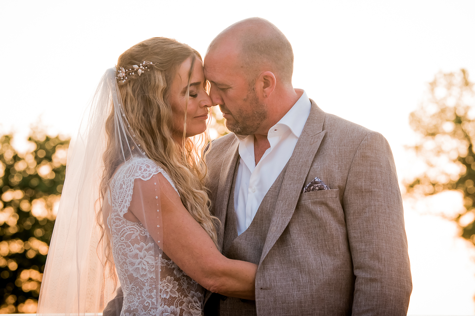 Echt moment trouwfoto: een bruidspaar gaan in elkaar op bij zonsondergang