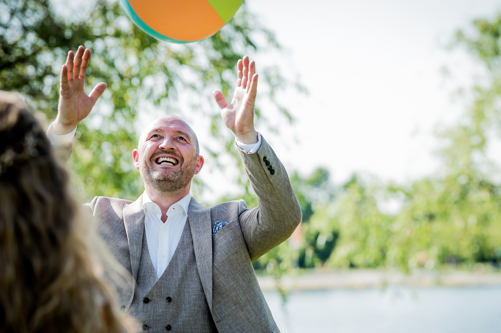 Echt moment trouwfoto: een bruidegom speelt met een strandbal