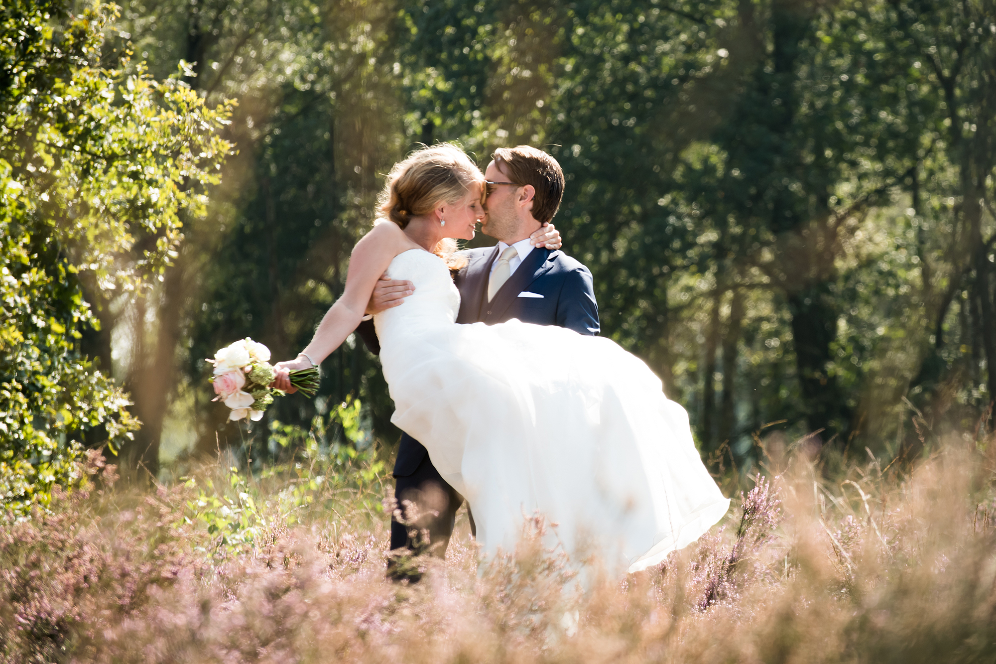 Emotionele trouwfotografie: bruidegom tilt bruid op op de heide in Venlo