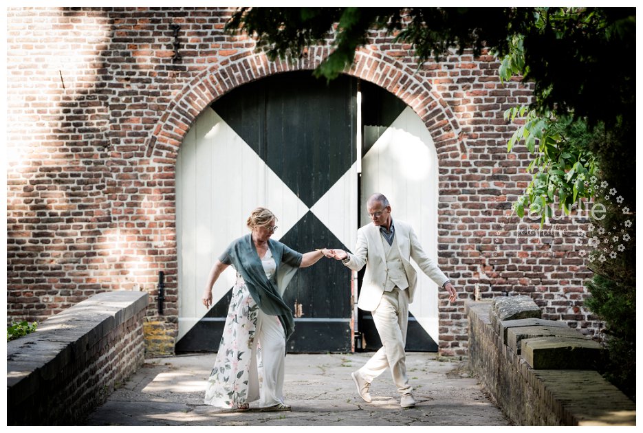 Trouwfotoshoot bij kasteel Terborgh: dansend bruidspaar bij poort