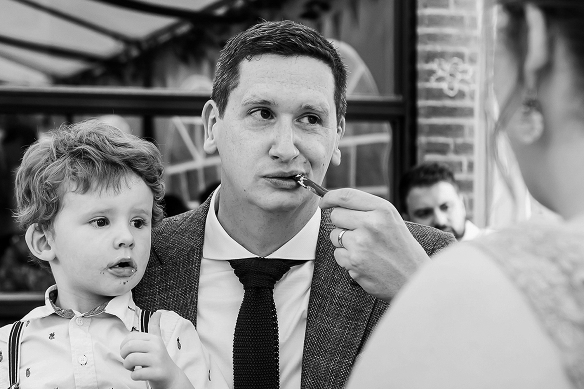 Bruidegom met zoon op schoot eten samen een stukje bruidstaart tijdens een trouwreportage in Heerlen