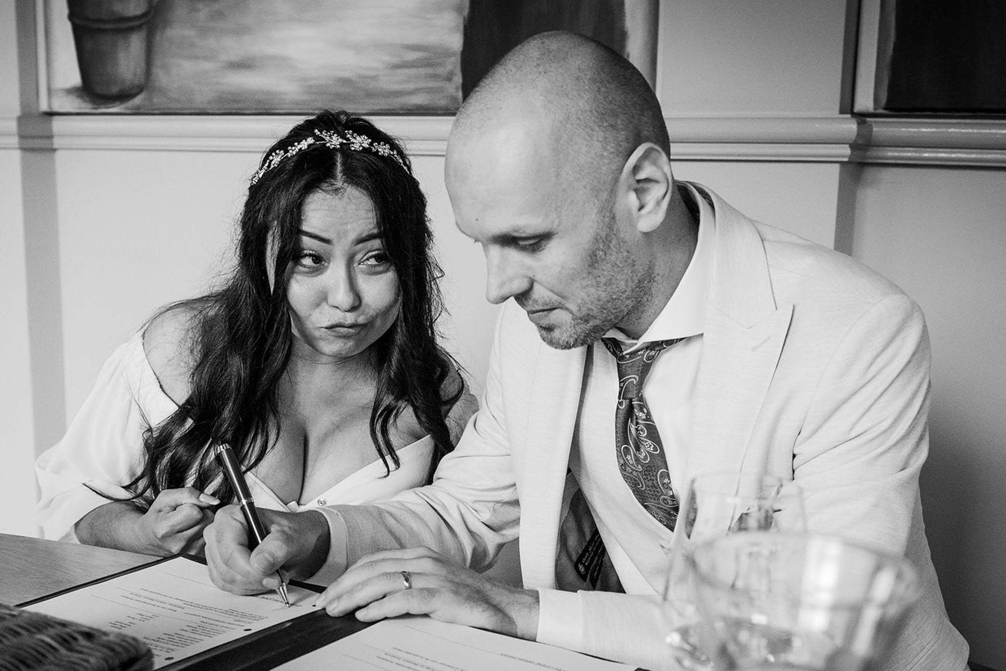 Bruid trekt gekke bek tijdens het tekenen van de trouwakte tijdens een bruidsreportage in Heerlen