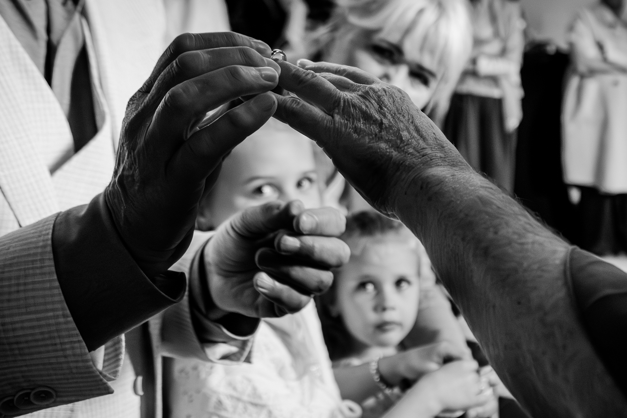 Kinderen staren gebiologeerd naar de hand van het bruidspaar die de trouwringen omdoen tijdens een journatistieke bruidsreportage