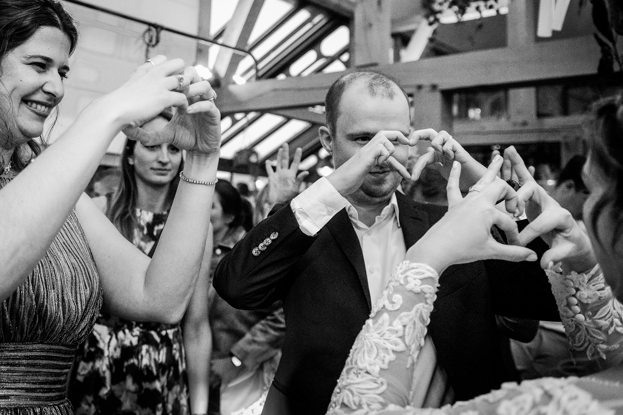 Gasten maken een hartjessymbool met hun handen tijdens een spontane trouwreportage
